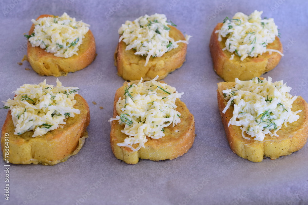 Pieces of toasted bread with cheese, fresh herbs and garlic topping