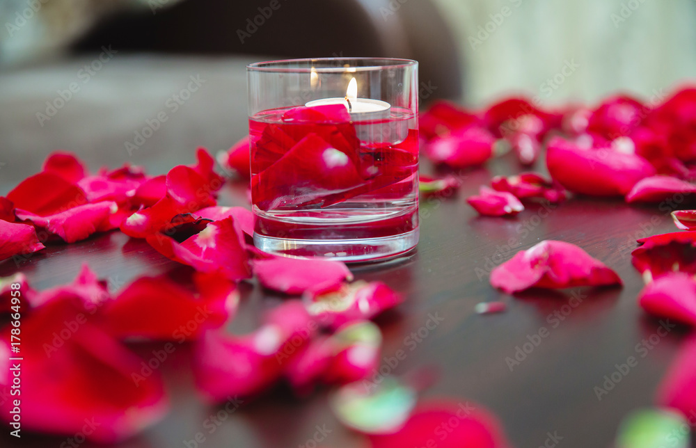 Beautiful romantic red candles with flower petals on dark wooden background