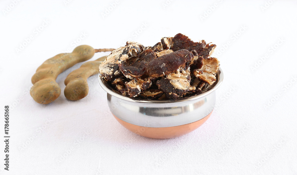 Tamarind fruit in a steel utensil and tamarind pods. Tamarind fruit in a steel utensil and tamarind pods.