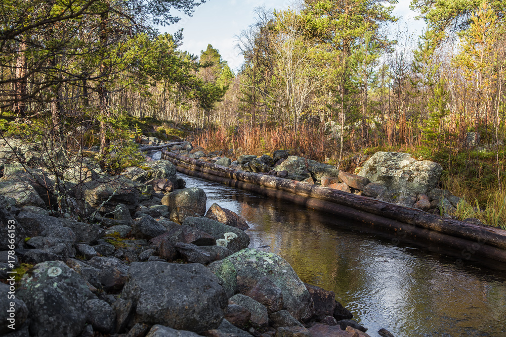 A beautiful autumn scenery of a historic water channel for transporting timber between lakes. Wooden construction.  Autumn in Femundsmarka National Park.