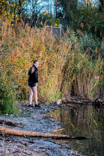 Jeune fille au bord d'un lac dans le Grand Parc de Miribel Jonage à l'automne