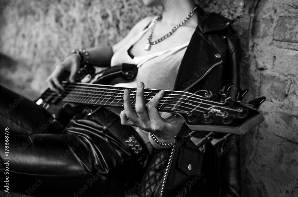 Obraz premium Close-up photo of electric guitar player in leather jacket. Black and white photo
