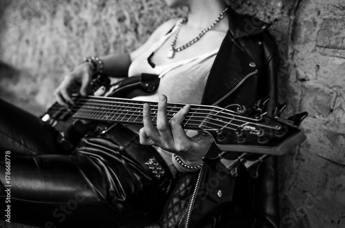 Close-up photo of electric guitar player in leather jacket. Black and white photo