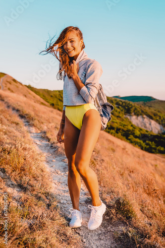 Smiling beautiful woman in nature at warm sunset. Happy girl on a walk in the mountains
