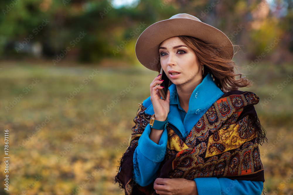 beautiful girl in a hat and coat talking on the phone