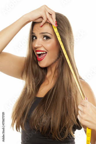 young happy beautiful woman measured her hair with a measuring tape