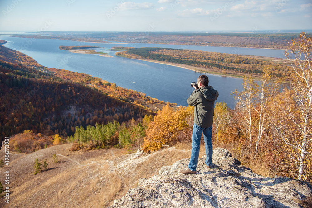a man stands on top of a mountain and takes a picture of the landscape