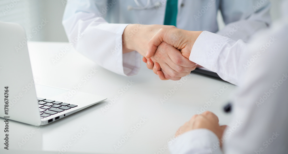 Doctor and patient shaking hands, close-up. Physician talking about medical examination results. Medicine, healthcare and trust concept Doctor and patient shaking hands, close-up. Physician talking about medical examination results. Medicine, healthcare and trust concept