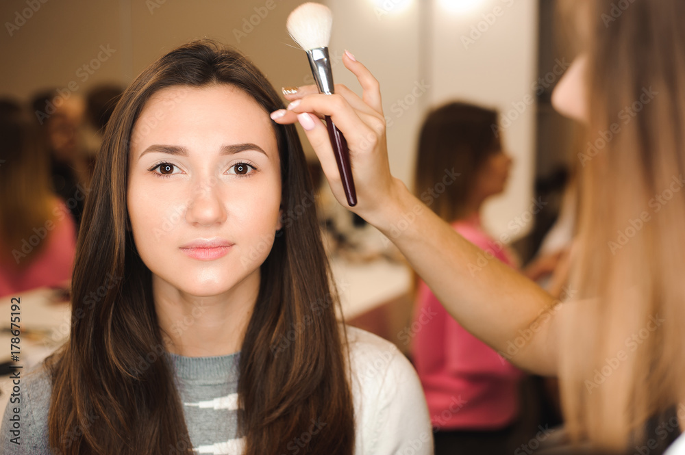 Make up artist doing professional make up of young woman. Beauty shcool.