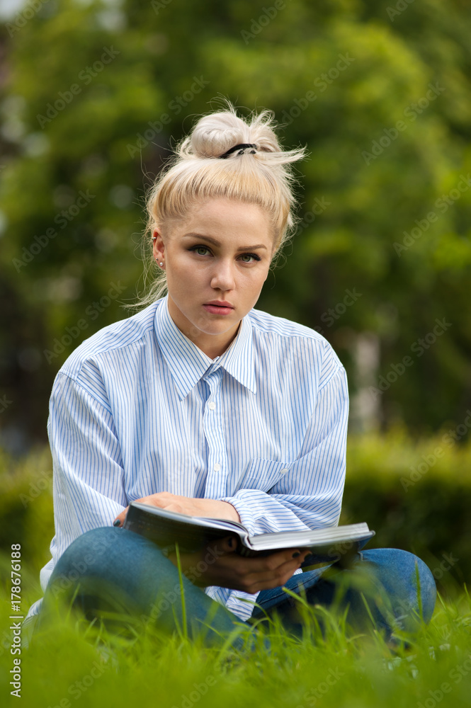 Pensive female student sitting with book in hands