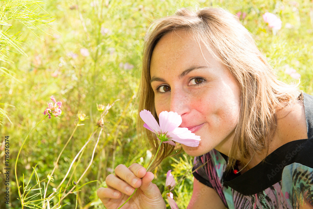 Young cute blonde woman smelling pink flowers Young cute blonde woman smelling pink flowers