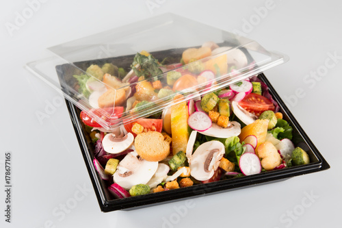 traditional salad in a black plastic container isolated on a white background