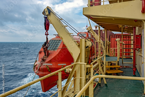 Red lifeboat hanging on a ship davits photo