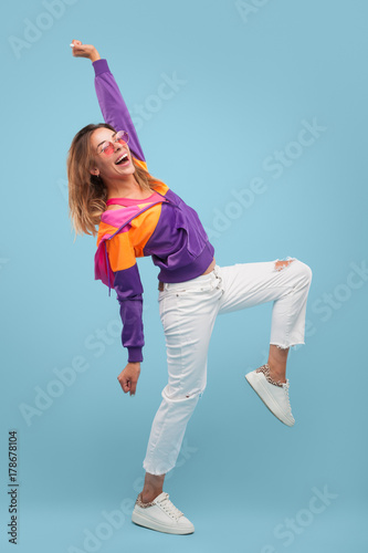 Fototapeta Naklejka Na Ścianę i Meble -  Stylish girl posing cheerfully on blue