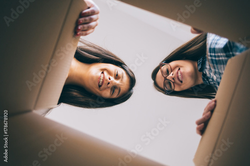  Smiling sisters unboxing received package photo
