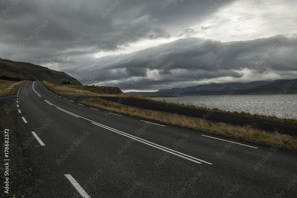 Fototapeta premium a deserted asphalt road running away into the hills. Iceland. The spirit of travel and adventure. 