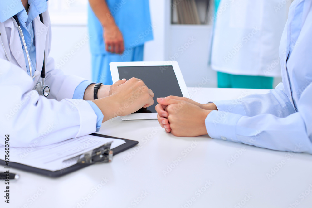 Doctor and patient are discussing something. Physician pointing into tablet computer Doctor and patient are discussing something. Physician pointing into tablet computer