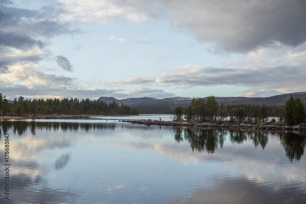 A beautiful lake landscape in Femundsmarka National Park in Norway. Lake with a distant mountains in background. Beautiful autumn scenery with vivid colors. A beautiful lake landscape in Femundsmarka National Park in Norway. Lake with a distant mountains in background. Beautiful autumn scenery with vivid colors.
