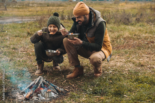 Father and son eating food on nature