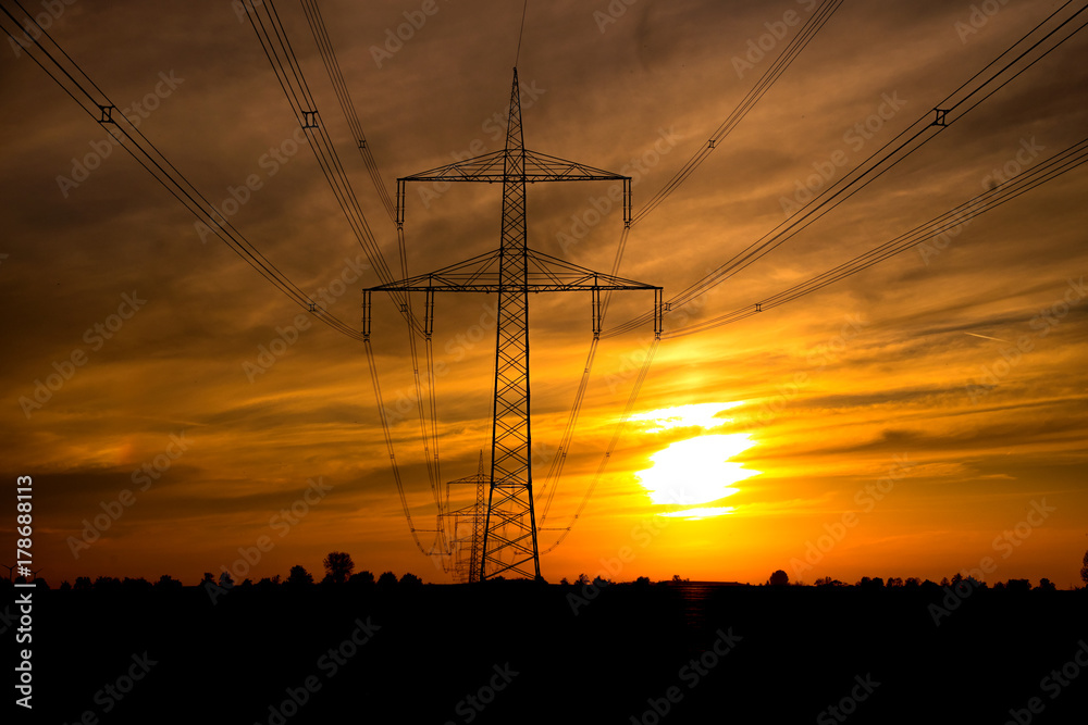 Strommast mit Leitungen im Sonnenuntergang