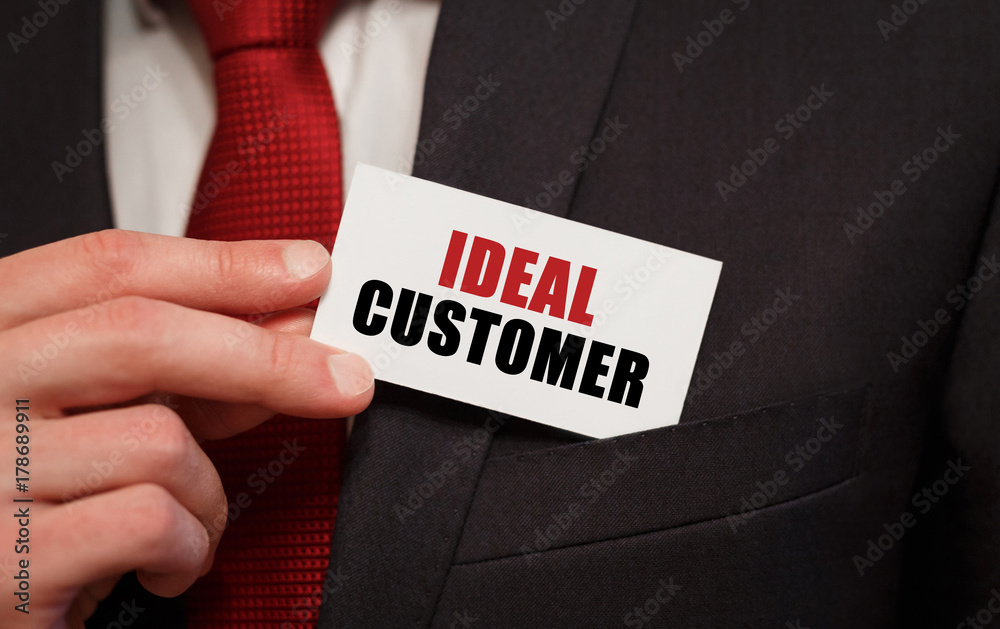 Businessman putting a card with text IDEAL CUSTOMER in the pocket Businessman putting a card with text IDEAL CUSTOMER in the pocket