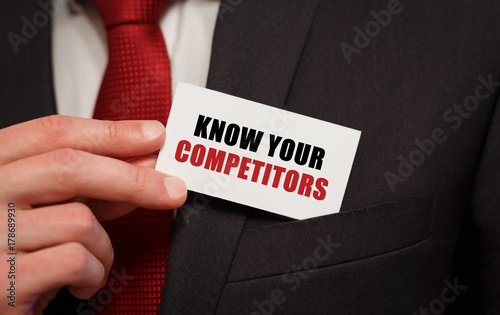 Canvas Print Businessman putting a card with text KNOW YOUR COMPETITORS in the pocket