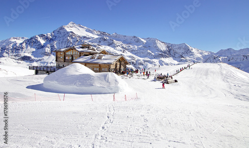 Downhill slope and apres ski mountain hut with restaurant terrace in the Italian Alps, Europe, Italy. Ski area Santa Caterina Valfurva