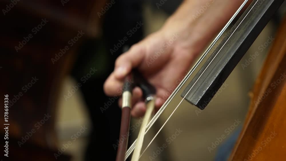 Hand playing violoncello with cello bow. Close up Hand playing violoncello with cello bow. Close up