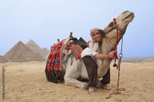 blonde Frau als Urlauberin umarmt ein Kamel vor den Pyramiden in   gypten