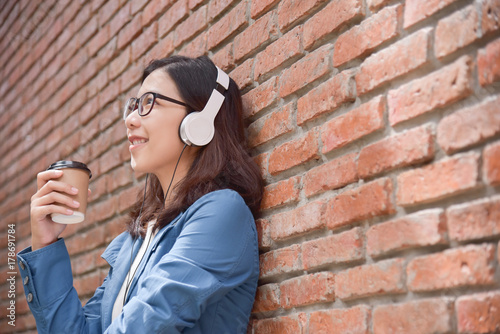 Woman in blue shirt listening to the music with headphone.