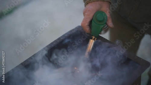 fire in the brazier. A hand fires a fire in a forged brazier with a long lighter photo