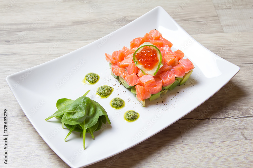 Tartare from salmon, caviar and avocado with pesto sauce and spinach. Close-up, selective focus.