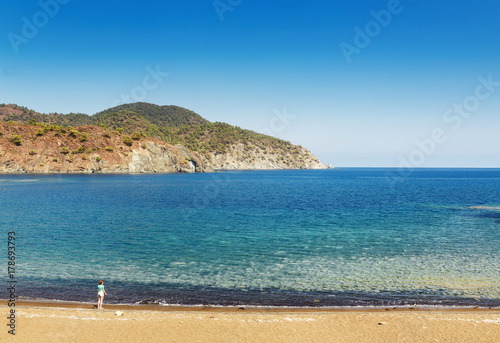 Small woman silhouette on a wild beach in solitary bay in mediterranean sea photo