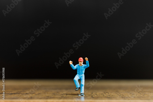 Miniature people worker on wooden floor with black background ,construction concept © Sirichai Puangsuwan