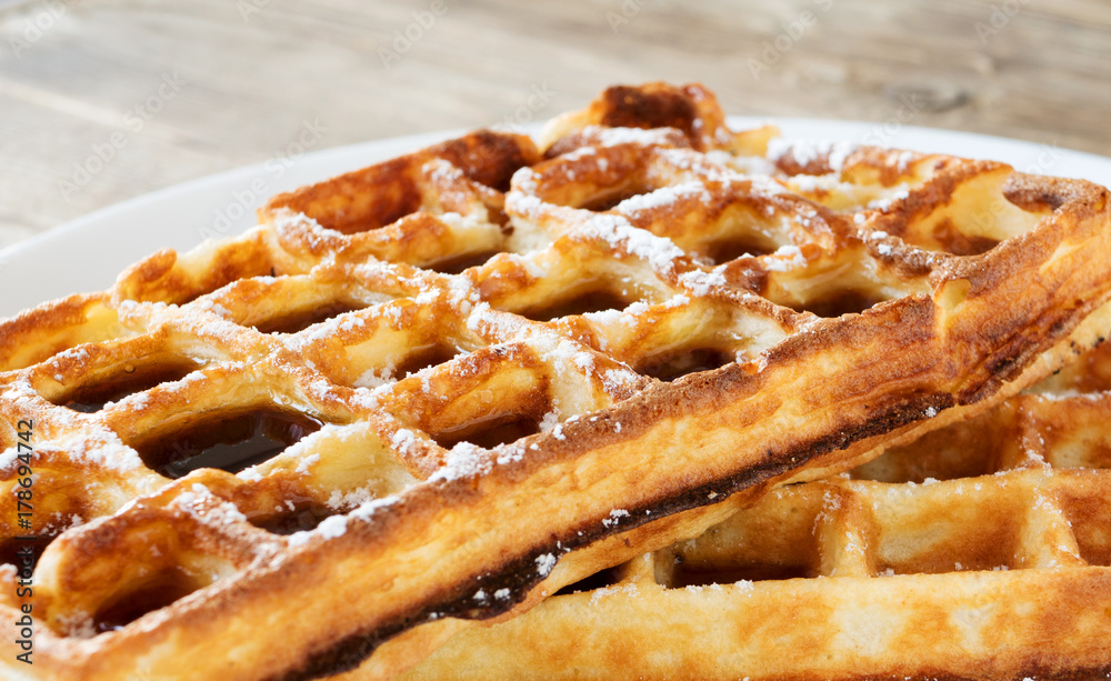 Sweet waffle with sugar powder and maple syrup topping on white plate. Tasty morning dessert Sweet waffle with sugar powder and maple syrup topping on white plate. Tasty morning dessert