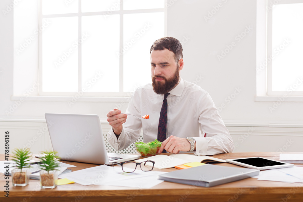 Busy man has business lunch in modern office interior