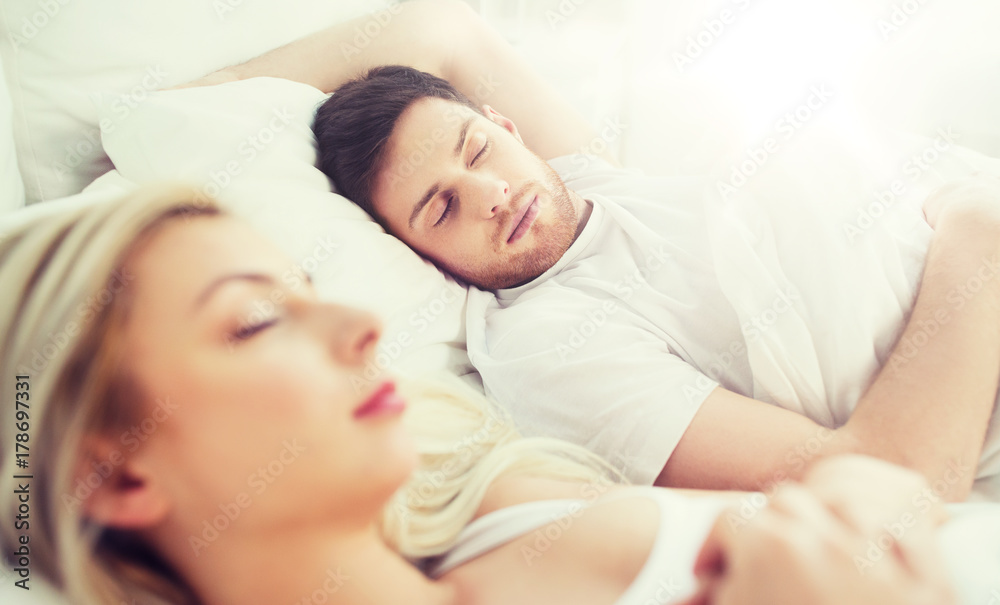 happy couple sleeping in bed at home