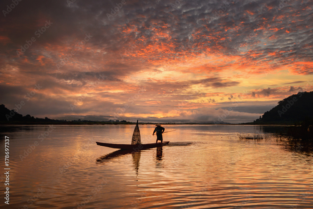 The silhouette fisherman boat in river  on during sunrise,Thailand