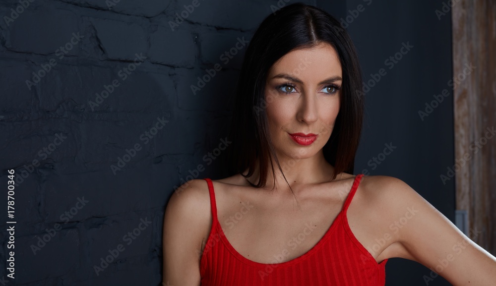 Young woman in red smiling against black wall Young woman in red smiling against black wall
