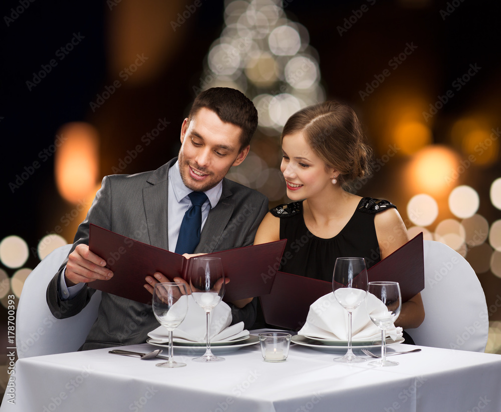 smiling couple with menus at christmas restaurant smiling couple with menus at christmas restaurant