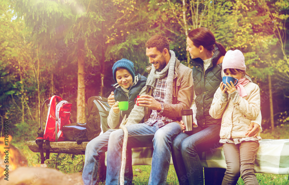 Fototapeta premium happy family sitting on bench at camp fire