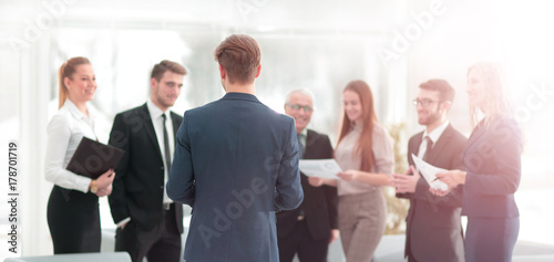 Successful business man standing with his staff in background at