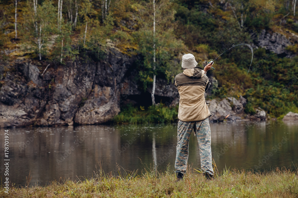 Fishing. The fisherman on a background of rocks throws the fishing rod into the water for catching fish. Concept rest, hobby Fishing. The fisherman on a background of rocks throws the fishing rod into the water for catching fish. Concept rest, hobby