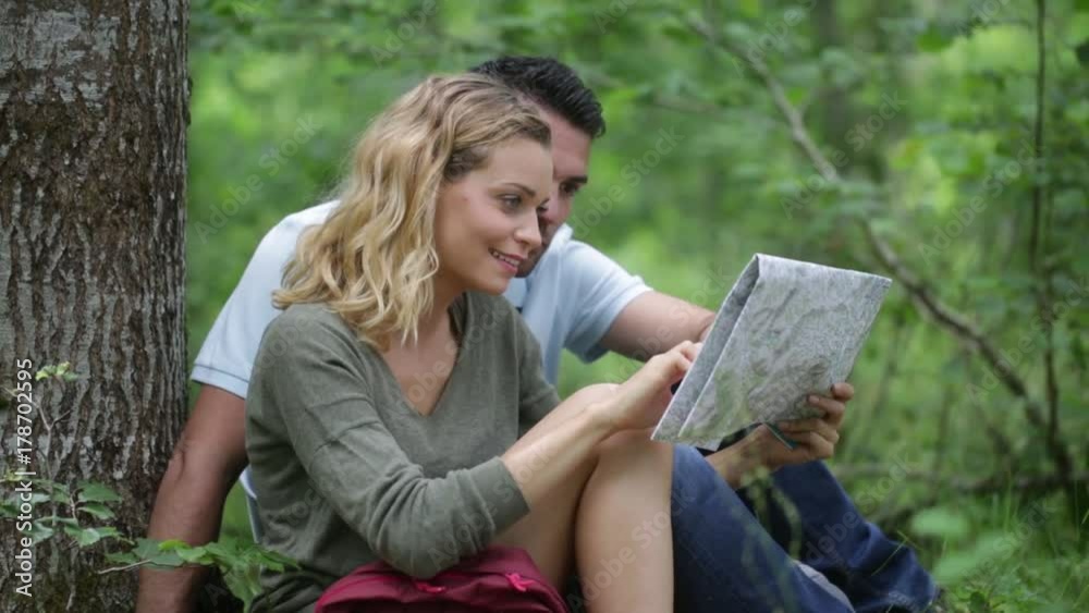 Hikers sat under a tree reading a map