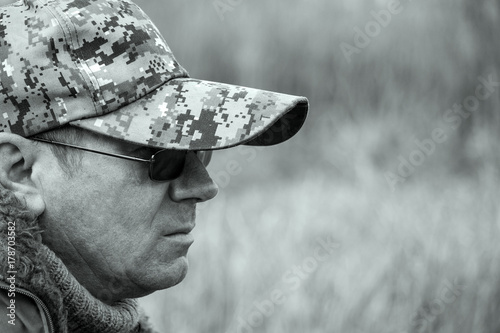 Portrait of a brutal man. The man in dark glasses, a warm sweater and a cap