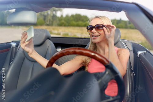 woman in convertible car taking selfie
