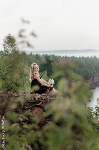 Sexy, beautiful girl seat on rock near the sea with flowers, american nature, Minnesota, space for text
