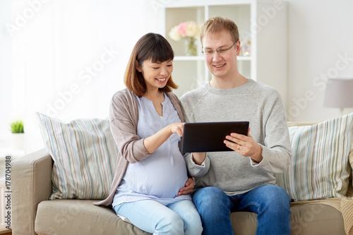 husband and pregnant wife with tablet pc at home