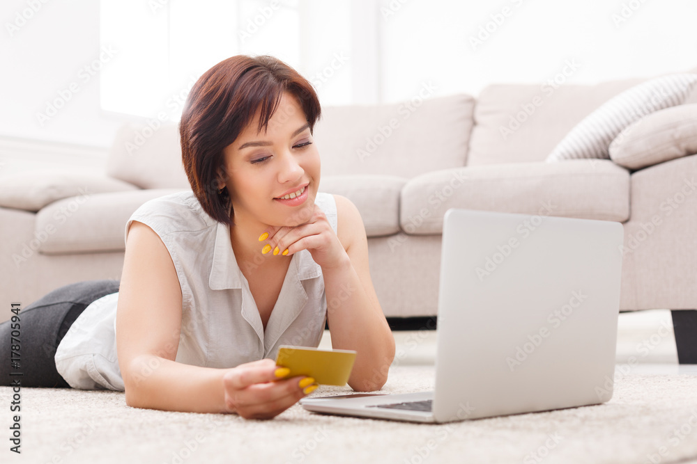 Smiling young girl shopping online on floor Smiling young girl shopping online on floor
