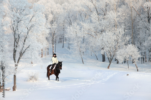 Pretty woman riding her horse through snow at Xmas morning 